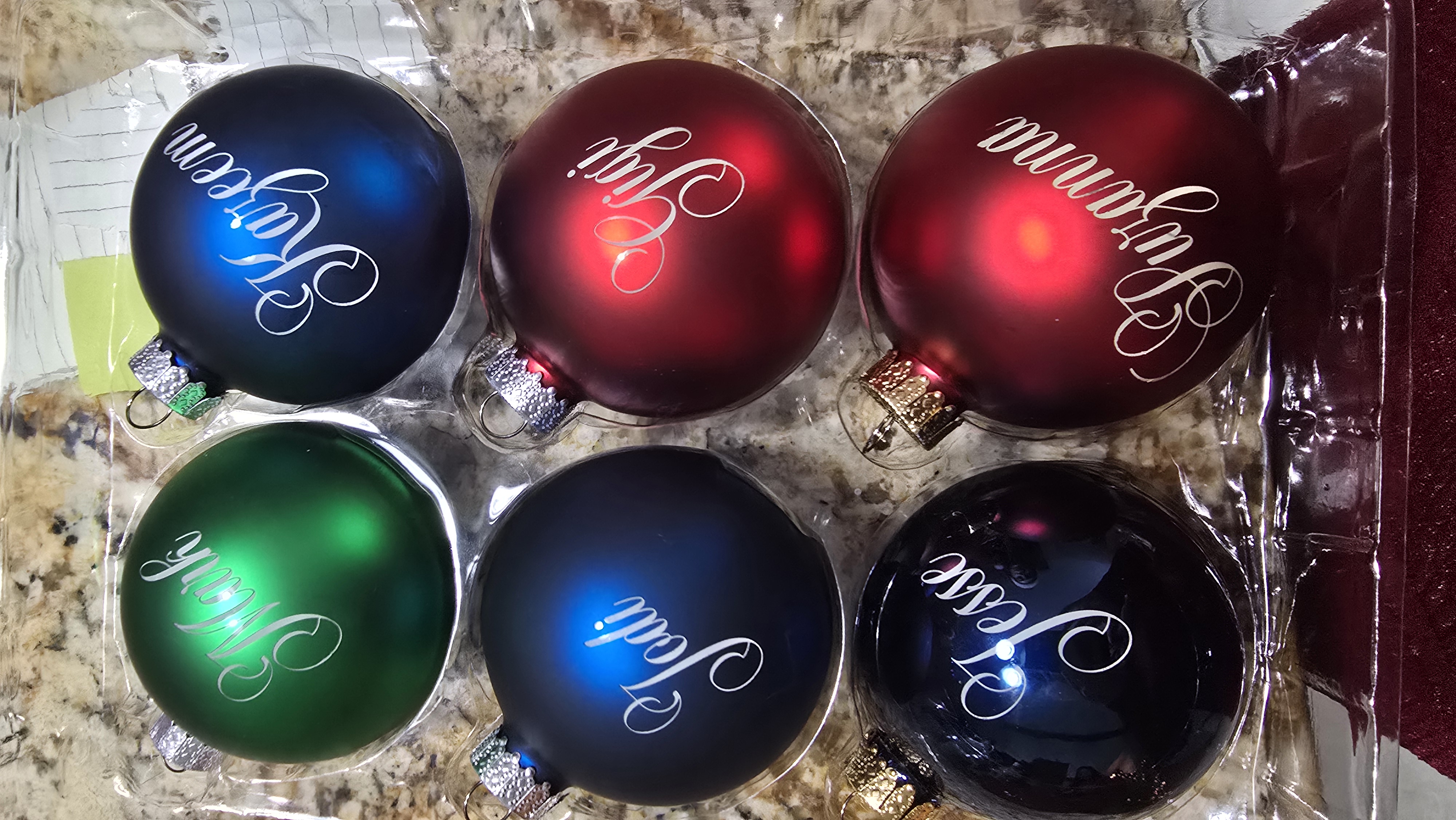 Collection of green, blue and red glass ornaments engraved with individual names
