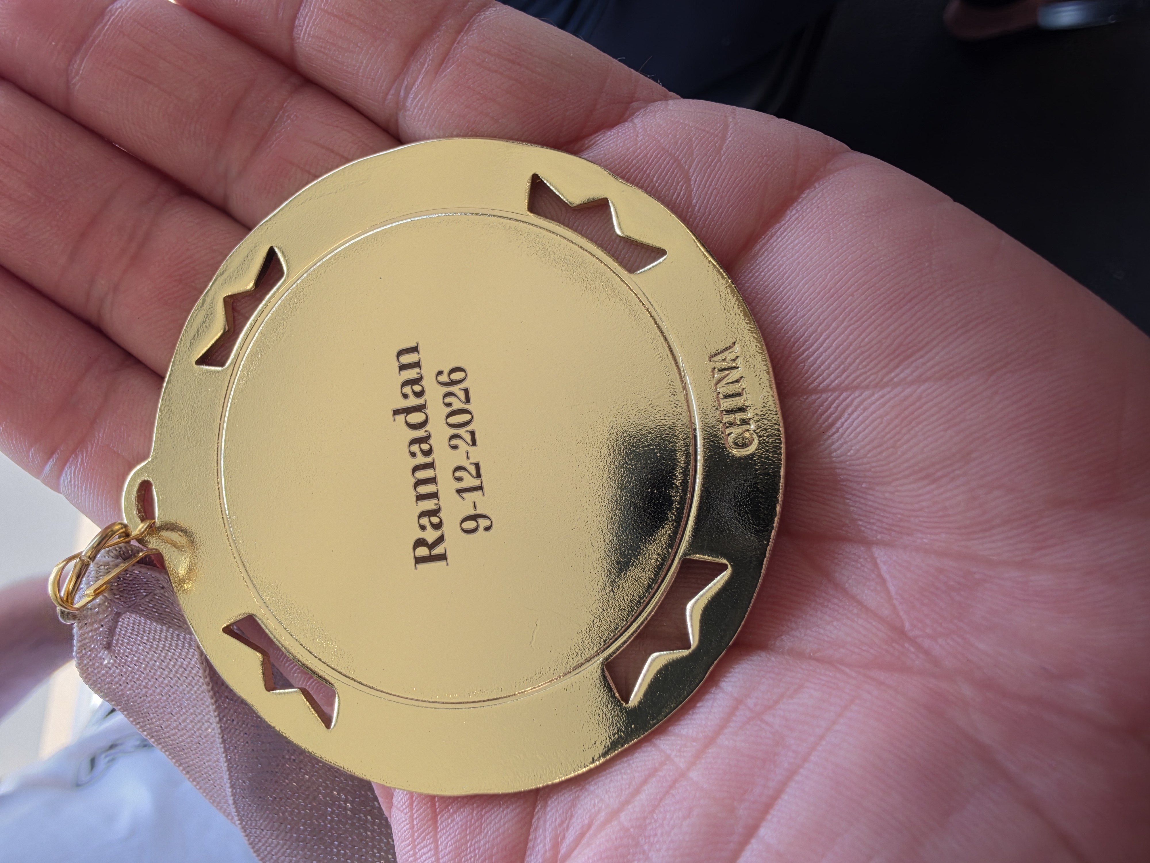 Back of a gold taekwondo medal personalized with an athlete name and event date