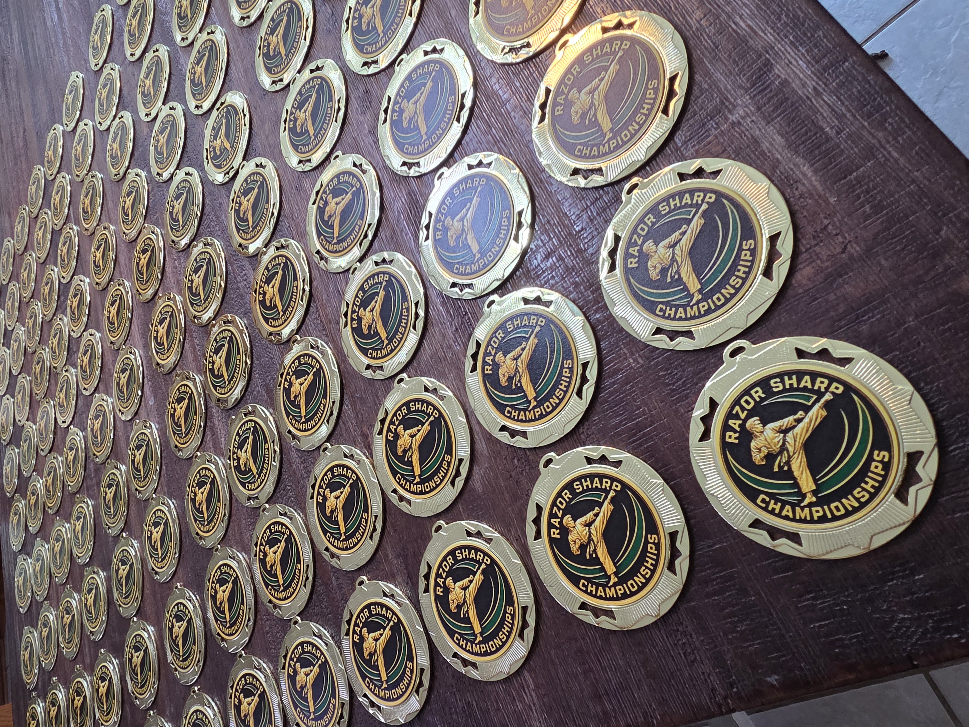 Rows of gold Razor Sharp Taekwondo Championship medals prepared for personalization